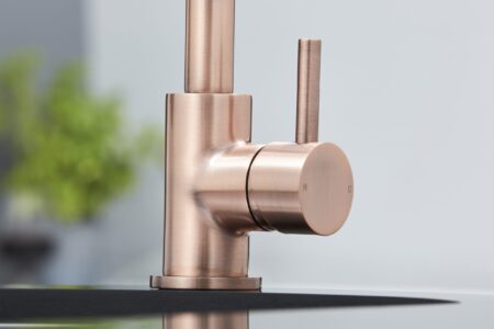 A modern copper finished kitchen tap in a bright kitchen.