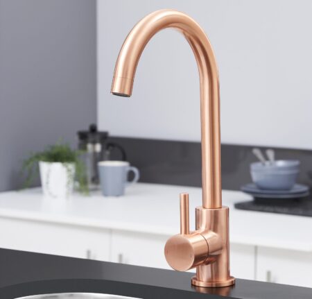 A modern, copper finished kitchen tap in a bright kitchen.